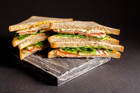 Sandwich with ham, cheese and vegetables on a black background.の写真素材