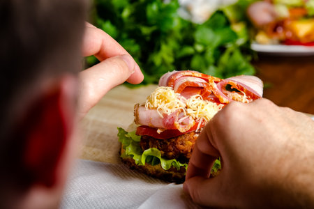 Man eating a sandwich with ham and cheese. Close-up.の写真素材