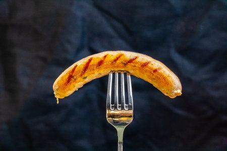 Grilled sausage on a fork on a dark background. Selective focusの写真素材