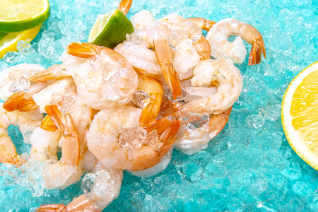 Frozen shrimps on ice with lemon slices and ice cubesの写真素材