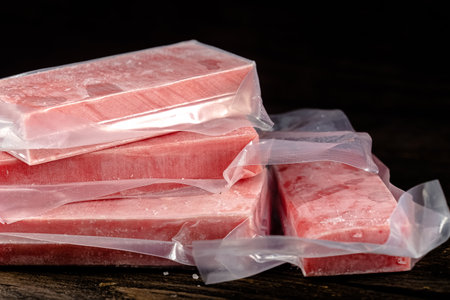 Three pieces of pink soap in plastic bag on dark wooden background.の写真素材