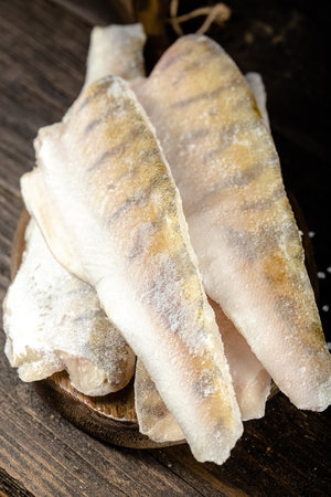 Fresh fish fillets in a wooden plate on a dark wooden backgroundの写真素材