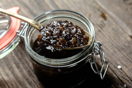 Fruit jam in a glass jar on a wooden background. Selective focus.の写真素材