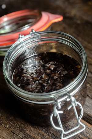 Black caviar in a glass jar on a rustic wooden background