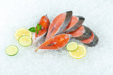 fresh raw salmon fish on ice with lemon and mint on white backgroundの写真素材