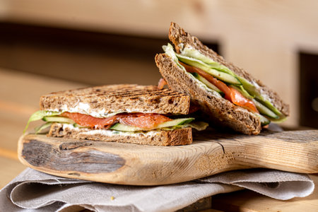 sandwich with salmon and cucumber on a wooden board, vertical