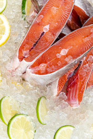 Fresh raw salmon on ice with lemon and lime, closeup view