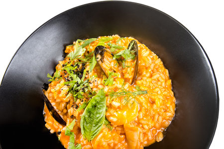 Risotto with mussels and parmesan cheese on black plateの写真素材