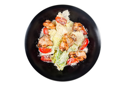 Caesar salad with grilled chicken on a black plate isolated on white backgroundの写真素材
