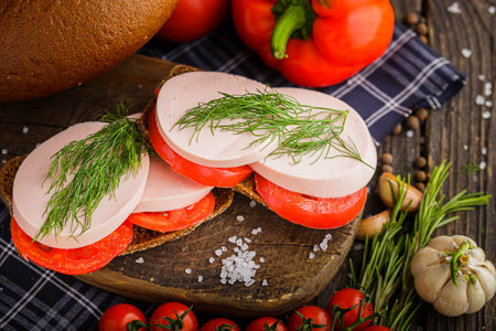 Sandwich with salami, tomatoes and herbs on a wooden backgroundの写真素材