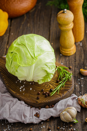 Fresh cabbage with rosemary, garlic and pepper on a wooden backgroundの写真素材
