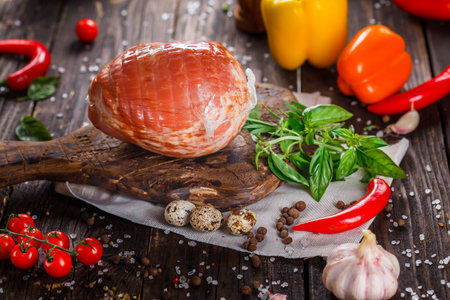 Smoked ham with herbs, spices and vegetables on a wooden backgroundの写真素材