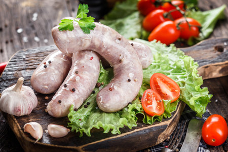 Raw sausages with herbs and vegetables on rustic wooden backgroundの写真素材