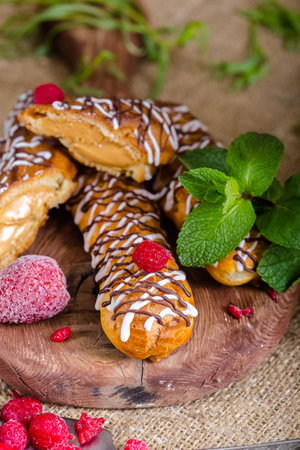 Delicious eclairs with raspberries and chocolate glaze