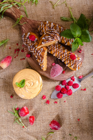 Chocolate waffles with cream and raspberries on a wooden board