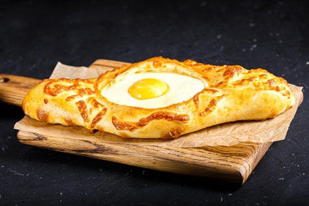 Georgian khachapuri with egg yolk on wooden board