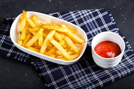 French fries with ketchup on a black background. Selective focus.