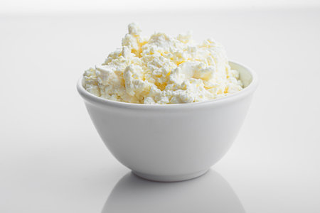 Cottage cheese in a bowl on a white background, close-up