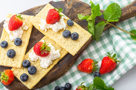 Crispbread with cottage cheese and fresh berries on wooden boardの写真素材