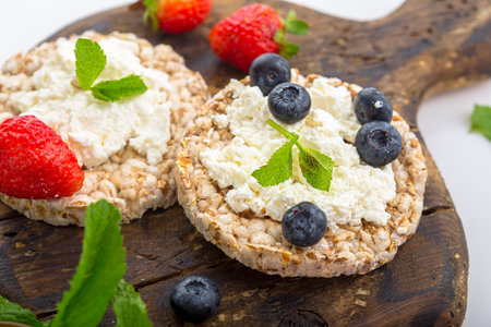 Crispbread with cottage cheese and fresh berries on wooden boardの写真素材