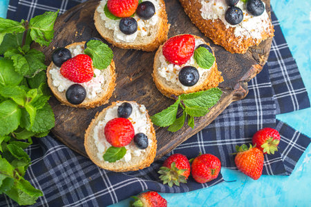 Crispbread with cottage cheese, berries and mint on a cutting boardの写真素材