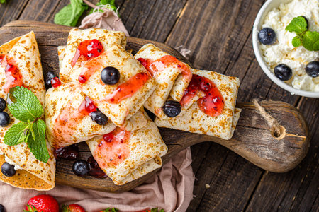 Pancakes with cottage cheese and berries on a wooden background.