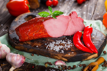 Smoked pork belly with spices and vegetables on a wooden background.の写真素材