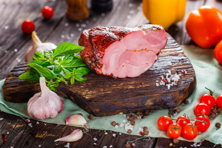 Smoked ham with spices and vegetables on a wooden background. Selective focus.の写真素材