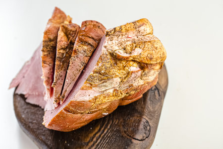 smoked ham on a wooden cutting board on a white background.の写真素材