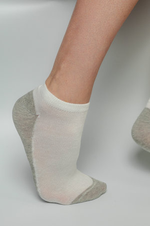 Legs of a young woman in socks on a gray background.