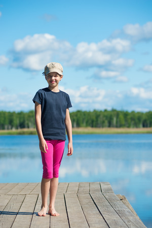 Girl on the river standing on the pierの写真素材