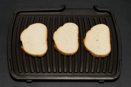 on a black background Three slices of bread on the grill