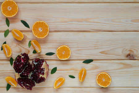 tangerines and pomegranate seeds collected in the corner of the boardの写真素材