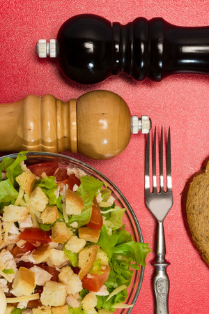 Caesar salad in the dish and salt and pepper on the tableの写真素材