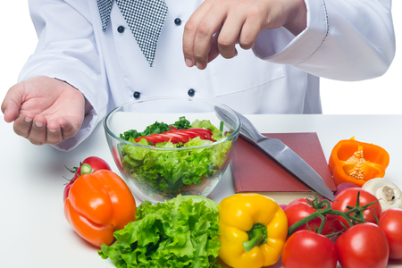 cook adds salt vegetable salad in a bowl on a tableの写真素材