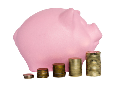 pink pig piggy bank and stacks of metal coinsの写真素材