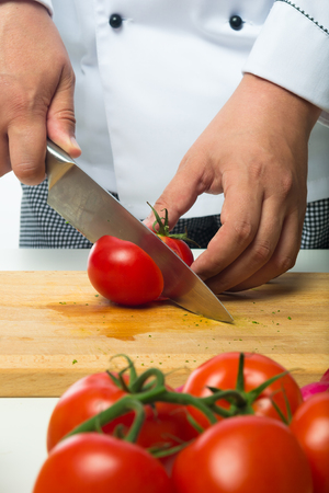 professional hands chopped tomatoes on a wooden boardの写真素材