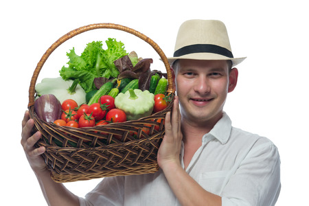 farmer in a hat and white shirt carries on his shoulder a basket of vegetablesの写真素材