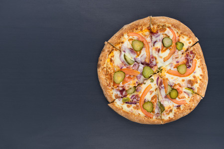 beautiful a whole pizza with cucumber lies on a black backgroundの写真素材