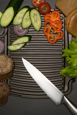 sliced vegetables with a knife laid on the grillの写真素材