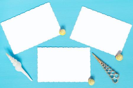 three sheets of white paper on a blue background with shellsの写真素材