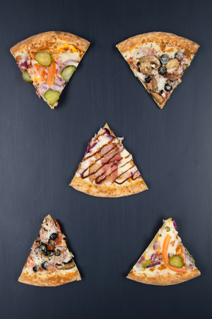 different pizza pieces arranged on a black tableの写真素材