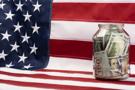 glass jar with dollars  standing on a US flagの写真素材