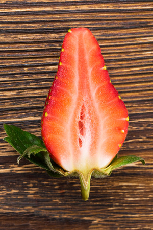 big red strawberry half on a dark table, domestic backgroundの写真素材