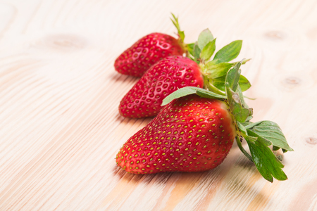 Three strawberries on a white board as backgroundの写真素材