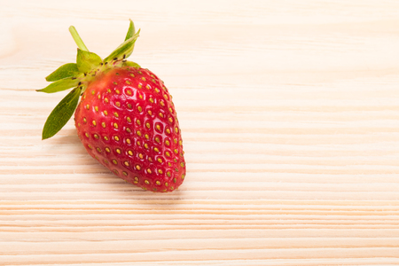 One red strawberry on the edge of the tableの写真素材