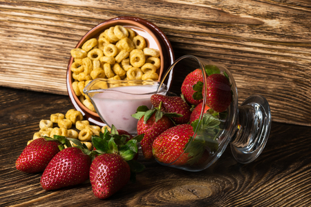 red strawberry next to corn flakes fell on a dark tableの写真素材