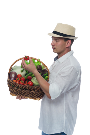 farmer pulled out of the basket with vegetables tomato and look at itの写真素材