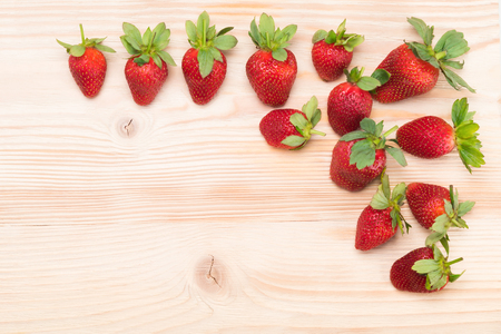 strawberry lies in the corner on a light wooden tableの写真素材