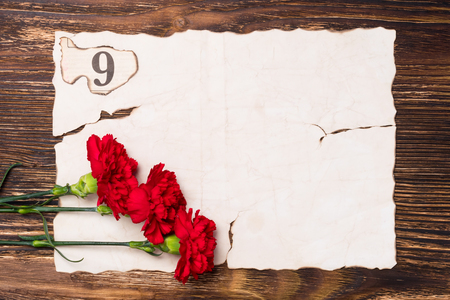 three red carnations on the sheet of old paper conceptの写真素材